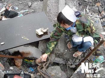 A nurse encourages a stranded child at the earthquake-hit Beichuan County, about 160 kilometers northeast of the epicenter of Wenchuan County, southwest China's Sichuan Province, May 13, 2008. Beichuan County is badly damaged in Monday's quake, with great numbers of buildings collapsed and landslides around the county.(Xinhua/Li Gang)