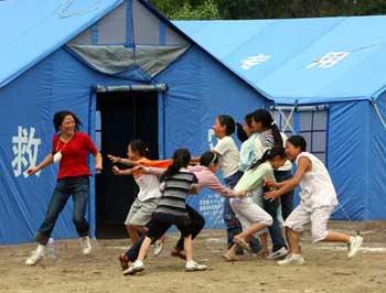 A teacher plays game with her pupils in a tent school in quake-hit Qingchuan County, southwest China's Sichuan Province, May 27, 2008. The large tent school composed of three former primary schools in the downtown area of Qingchuan opened on Tuesday. A total of 500 pupils resumed class in 30 tent classrooms. (Xinhua Photo)