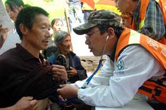 A medical worker (R) from east China's Zhejiang Province examines a local man at Qinggang Village, Gucheng Town, Pingwu County, in southwest China's Sichuan Province, on May 23, 2008. Large numbers of medical workers have arrived at local villages in the quake-hit area in Sichuan Province to provide medical treatment and health services.(Xinhua Photo)