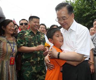 Chinese Premier Wen Jiabao (R Front) embraces Wang Shichen, a 12-year-old primary school pupil of grade six, when he inspects the resettlement at Meirui Textile Company in Mianyang, a city in quake-hit southwest China's Sichuan Province, June 6, 2008. (Xinhua Photo)