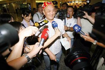 The first passenger to step out the plane from the first group of mainland tourists of the day to arrive in Taiwan from Guangzhou, is surrounded by reporters at the Taoyuan International Airport July 4, 2008. 