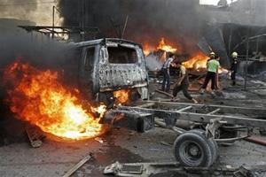 Men try to put fire out after a car bomb blast in Abu Dshir in Baghdad, Iraq, Friday, Oct. 10, 2008. A parked car bomb killed 13 people in a market in Abu Dshir Friday. At least 27 people were wounded.(AP Photo/Loay Hameed)