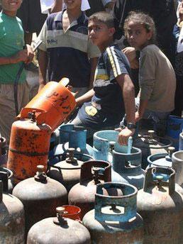 Palestinians queue with their cooking gas bottles at a station in the central Gaza Strip refugee camp of al-Nusseirat on August 2008. Israel said it will maintain its closure of the Gaza Strip despite international concern over a deterioration of the humanitarian situation in the aid-dependent Palestinian territory.(AFP)