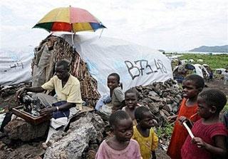 Children watch as a Congolese man sews on December 6, 2008 at Mugunga camp for internally displaced people (IDP), in Goma.(AFP/File/Pascal Guyot)