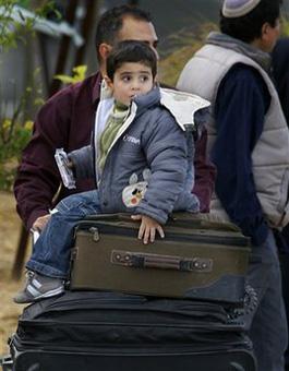 A young boy sits atop suitcases as he is pushed on a luggage trolley while arriving to the Israeli side of the Erez crossing, after leaving the Gaza Strip, Thursday, Jan. 8, 2009. (AP Photo/Anja Niedringhaus)