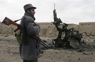 An Afghan policeman is seen near a destroyed vehicle which was used by a suicide bomber in Chaparhar district of Ningarhar province, east of Kabul, Afghanistan, on Saturday, Jan. 17, 2009.  (AP Photo/Rahmat Gul)