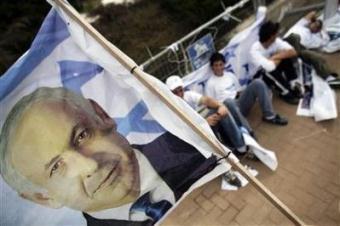 Campaign workers for Israel's Likud party sit behind a flag depicting party leader Benjamin Netanyahu in Kiryat Malachi, near Ashkelon, February 9, 2009.(Damir Sagolj/Reuters)