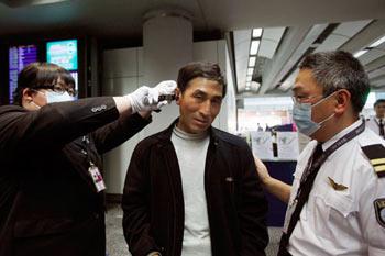 Staff members check the temperature of a passenger at Hong Kong International Airport in Hong Kong, south China, April 27, 2009. Hong Kong Special Administrative Region has taken measures to contain the possible spread of swine flu.(Xinhua Photo)