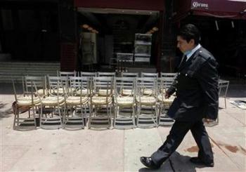 A man walks in front of a closed restaurant in Mexico City May 4, 2009. Mexican businesses will resume regular activities as planned on Wednesday after a five-day shutdown due to the fatal flu outbreak, the health minister said on Monday.