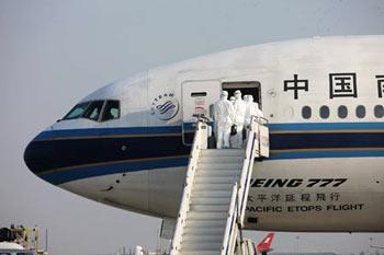 Inspectors walk aboard the chartered plane from Mexico to check the health of Chinese citizens from Mexico after the plane arrived in Shanghai on May 6, 2009. The chartered plane sent to fetch Chinese citizens from Mexico arrived in Shanghai Wednesday afternoon, with 98 passengers and 21 crew members on board. (Xinhua/Xing Guangli)