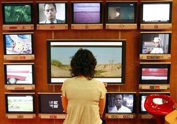 A visitor looks at television programmes during the annual MIPCOM television programme market in Cannes, southeastern France, Oct. 13, 2008. (Xinhua/Reuters Photo)